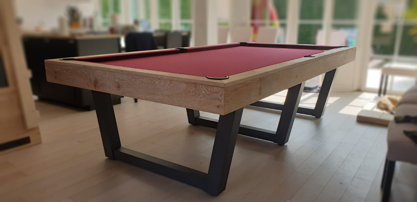 Cette grande table à 3 pieds métalliques gris anthracite en forme de V est un billard convertible HARMONY-V 280 finition chêne brossé huilé 1804 avec tissu couleur wine. On aperçoit un des 3 éléments du plateau ST avec décor central gris anthracite sur la gauche de l'image. L'achat de ce billard convertible en table permet à notre client d'attabler jusqu'à 16 convives agréablement.